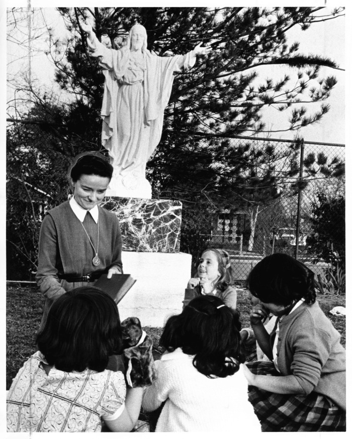Canoga Park, CA - Our Lady of Guadalupe Center - Sister Michaela gathers children at foot of our Lady of Guadalupe statue to read a story (Noted: The statue appears to be of Jesus rather than Mary)